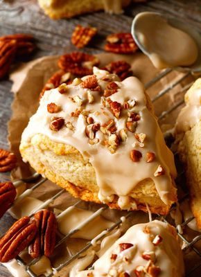 A pastry covered in icing and nuts on top of a cooling rack.