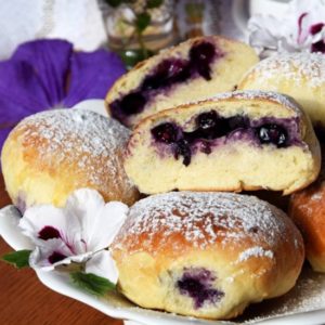 A plate of blueberry filled doughnuts on top of a table.
