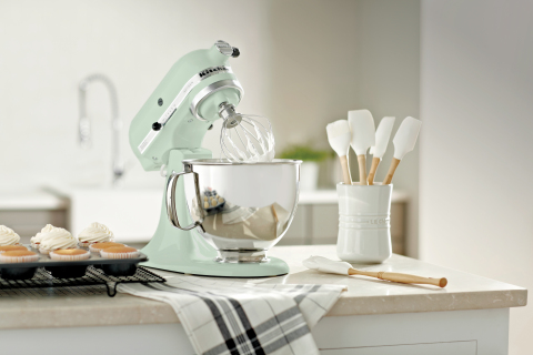 A kitchen mixer on the counter with some utensils