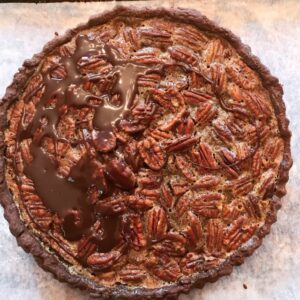 A chocolate pecan pie sitting on top of parchment paper.