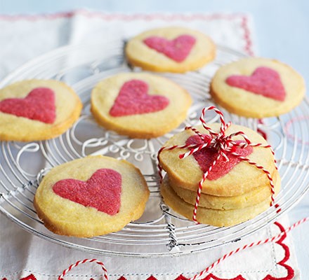 A plate of heart shaped cookies on top of a table.