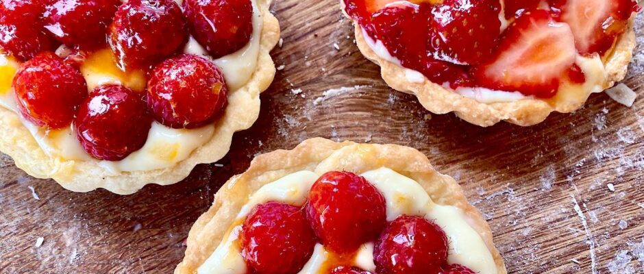 Three small tarts with strawberries on top of them.