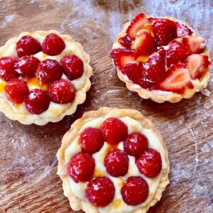 Three small tarts with strawberries on top of them.