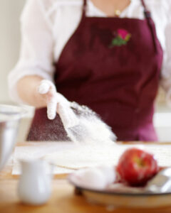 A person in an apron is using flour to make something.