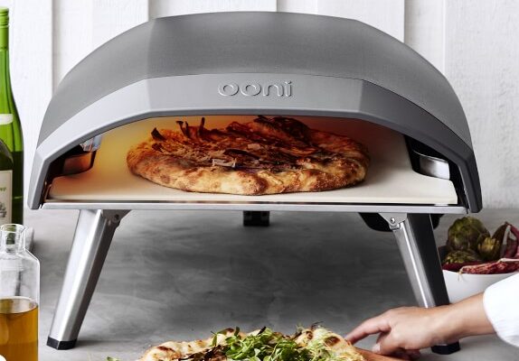 A person is putting pizza into an oven.